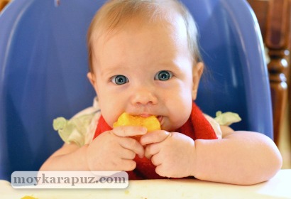 Малыш пробует кусочек фрукта