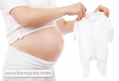 Беременная подготавливает вещи для будущего ребенка